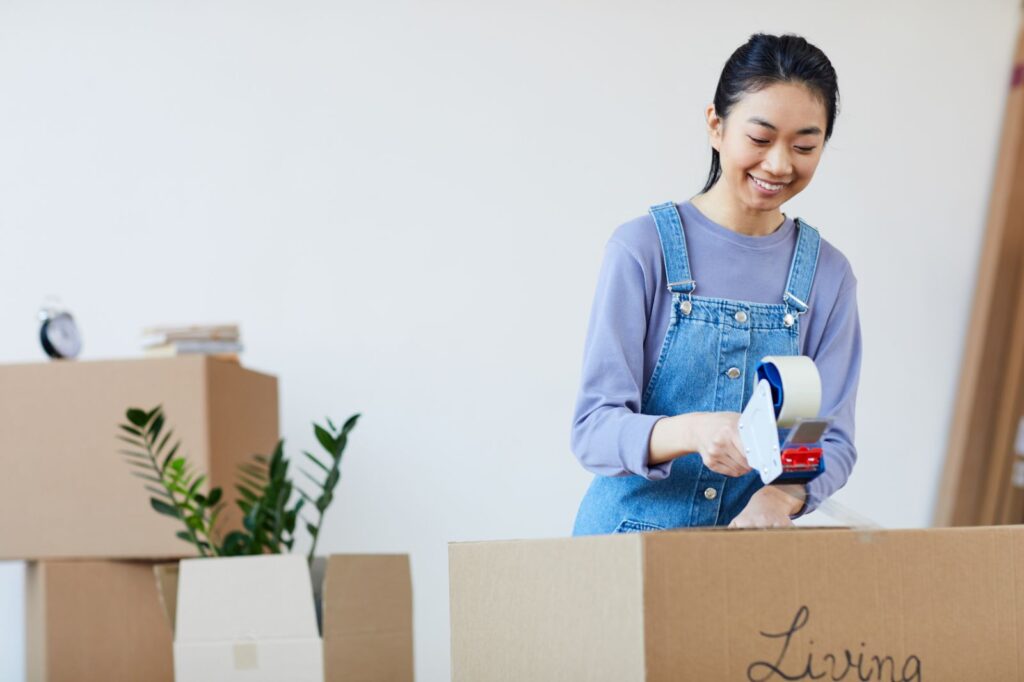 a young lady sealing a carton